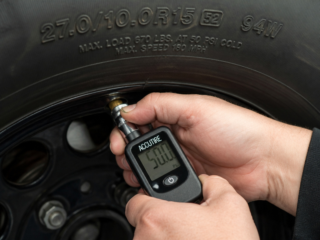 Checking tire pressure on a wider tire installed on a stock alloy wheel.
