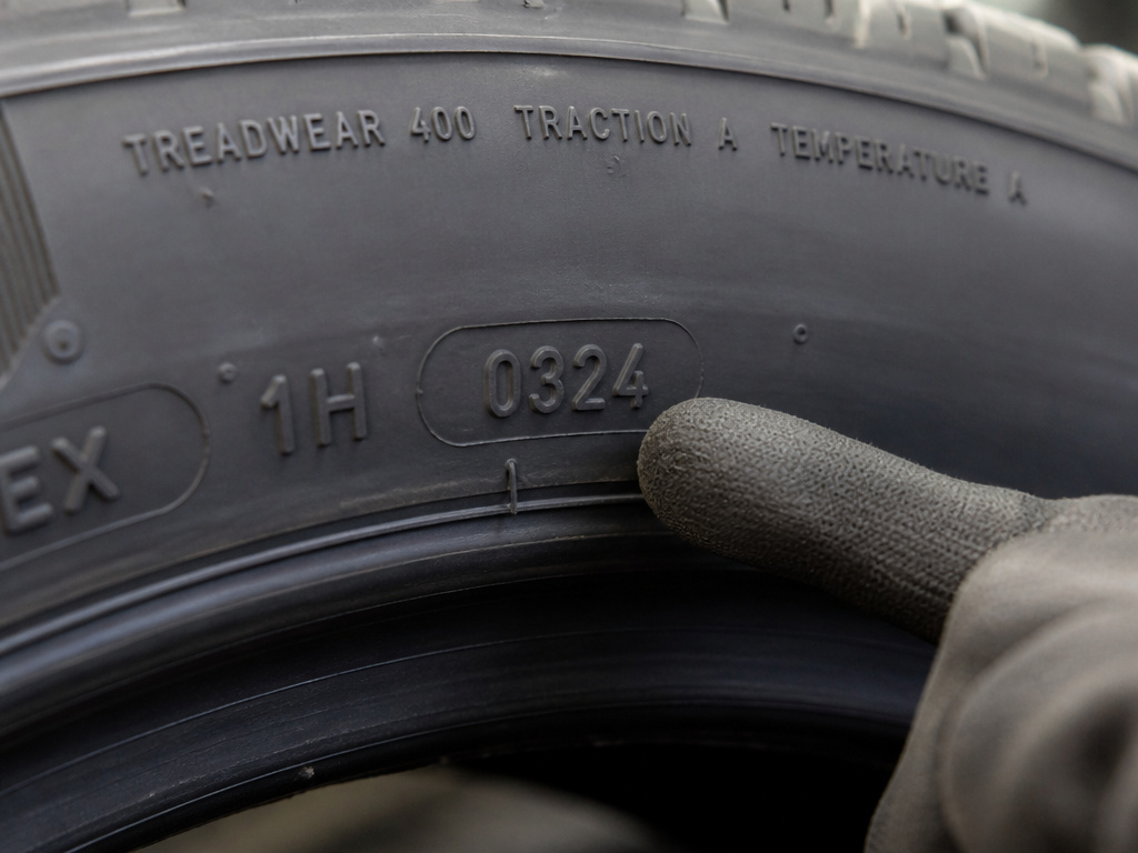 Close-up of a tire's TIN manufacturing date code and UTQG grades on sidewall.